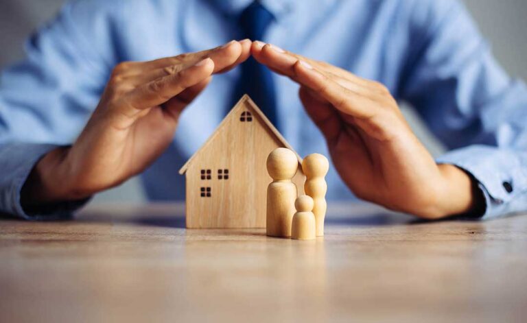 A couple reviews life insurance papers, a household budget, and a calculator at a kitchen table.